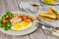 Traditional English breakfast with bacon, eggs, sausages, salad and grilled cheese toast Royalty Free Stock Photo