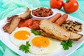 Traditional English breakfast: bacon, mushrooms, eggs, tomatoes, sausages, beans, toast on a white plate Royalty Free Stock Photo