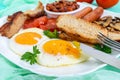 Traditional English breakfast: bacon, mushrooms, eggs, tomatoes, sausages, beans, toast on a white plate Royalty Free Stock Photo