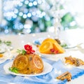 Traditional English Christmas pudding decorated with oranges and flowers in a festive table setting with fruits, spices Royalty Free Stock Photo
