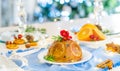 Traditional English Christmas pudding decorated with oranges and flowers in a festive table setting with fruits, spices Royalty Free Stock Photo