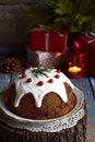 Traditional english Christmas steamed pudding with winter berries, dried fruits, nut in festive setting with Xmas tree and burning