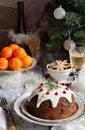Traditional english Christmas steamed pudding with winter berries, dried fruits, nut in festive setting with Xmas tree and burning Royalty Free Stock Photo