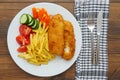 Traditional english dish with battered white cod, french fries and fresh vegetable served on a white plate