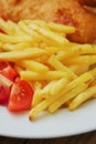 Traditional english dish with battered white cod, french fries and fresh vegetable served on a white plate. Close up. Vertical