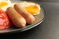 traditional English European Breakfast eggs sausage and salad vegetables red tomatoes on a gray plate on a black background close Royalty Free Stock Photo