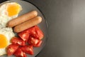 Traditional English European Breakfast eggs sausage and salad vegetables red tomatoes on a gray plate on a black background close Royalty Free Stock Photo