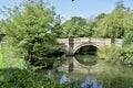 Traditional English Stone Bridge over a river surrounded by trees with reflection in the water. Yorkshire, UK.