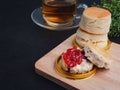 Traditional English style scones delicious freshly baked homemade with strawberry jam on a wooden cutting board and teacup on a Royalty Free Stock Photo