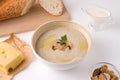 mushroom cream champignon soup next to cheese, cream, crackers and baguette on a white background