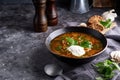 Traditional European and Russian soup borsch with cabbage, sour cream and meat served in a plate on a dark stone table