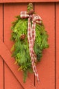 Traditional evergreen Christmas swag with plaid bow hung on pain Royalty Free Stock Photo