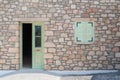 Traditional facade of old masonry house with door and window. Old stone facade of house with half way opened door and shut window