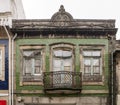 Traditional facade of old Portuguese architecture house with green tiles and metal balcony. Weathered, broken windows. Royalty Free Stock Photo