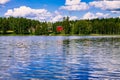 A traditional Finnish wooden cottage with a sauna and a barn on the lake shore. Summer rural Finland.