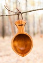 Traditional Finnish wooden mug `Kuksa` hanging on a tree in the autumn forest