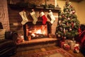 a traditional fireplace with a decorated tree and presents underneath, next to stockings hung by the chimney Royalty Free Stock Photo