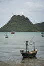 Traditional fishing boat laying on a beach near the sea with big and long mountain in background,cloudy sky,filtered image Royalty Free Stock Photo