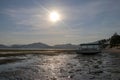 Traditional fishing boat moored at sandy beach using an anchor rope. Laminate boat with wooden roof tied up by shore at low tide. Royalty Free Stock Photo