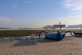 Traditional fishing boat moored at sandy beach using an anchor rope. Laminate boat with wooden roof tied up by shore at low tide. Royalty Free Stock Photo