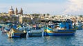 Traditional fishing boats luzzu and churches in Marsaxlokk