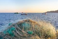 Traditional fishing net and small fishing boats behind. Traditional jobs by the Mediterranean sea. Sunset time, blurry background