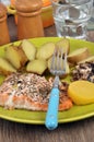 Plate of herbed salmon with potatoes and a slice of lemon served at the table with a glass of water Royalty Free Stock Photo