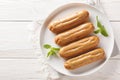 Traditional French dessert Eclairs with custard and topped with caramels icing close-up in a plate. Horizontal top view