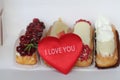 Traditional French dessert with plush heart and an inscription I Love You. Beautiful eclairs with icing and berries. Royalty Free Stock Photo