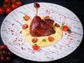 Duck leg confit with mashed potatoes and blue cheese, grapes and tomatoes