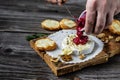 Traditional French homemade baked Camembert cheese Cranberry sauce is poured over cheese from a jug. On cheese rosemary and Royalty Free Stock Photo