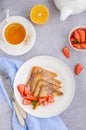 Traditional French toast sprinkled with powdered sugar with fresh strawberries on a white plate with a cup of tea. Royalty Free Stock Photo