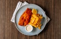 Traditional fried Fish and chips with tartar sauce in white plate on dark wooden background top view Royalty Free Stock Photo