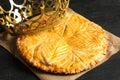 Traditional galette des Rois with decorative crown on black table, closeup