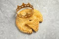 Traditional galette des Rois with paper crown on light grey marble table, above view