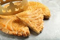 Traditional galette des Rois with paper crown on light grey marble table, closeup