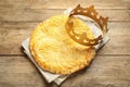 Traditional galette des Rois with paper crown on wooden table, flat lay