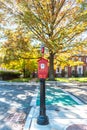 Traditional Game Well Boston fire alarm station box on a pedestal in front of beautiful fall trees on a sunny fall day