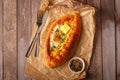 Traditional Georgian dish khachapuri ajarian on rustic wooden kitchen table background.