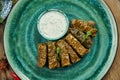 Traditional Georgian dolma - rice with minced meat in grape leaves on a blue plate with yogurt sauce. Wood background. Top view. Royalty Free Stock Photo