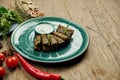 Traditional Georgian dolma - rice with minced meat in grape leaves on a blue plate with yogurt sauce. Wood background. Top view. Royalty Free Stock Photo