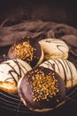 Traditional german Berliner pastries glazed with dark and white chocolate and hazelnut brittle on brown background