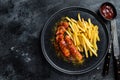 Traditional German currywurst, served with French fries. Black background. Top view. Copy space Royalty Free Stock Photo