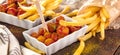 Traditional German currywurst, served with pommes on wooden background.