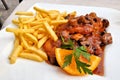 German Jagerschnitzel with a mushroom gravy and french fries, close up on a white plate Royalty Free Stock Photo