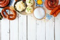 Traditional German Oktoberfest meal top border on a white wood background