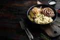 Traditional German Sausages with Mashed Potatoes and Sauerkraut in cast iron frying pan, on old dark  wooden table background , Royalty Free Stock Photo