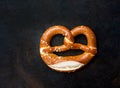 Traditional German Savory Lye Pretzel with Salt on Dark Rustic Rusty Baking Tray Background. Poster Banner for Bakery