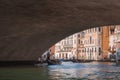 Traditional gondola passing under bridge in Venice, Italy on a sunny day. Royalty Free Stock Photo