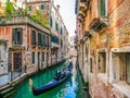 Traditional Gondolas on narrow canal between colorful houses, Venice, Italy